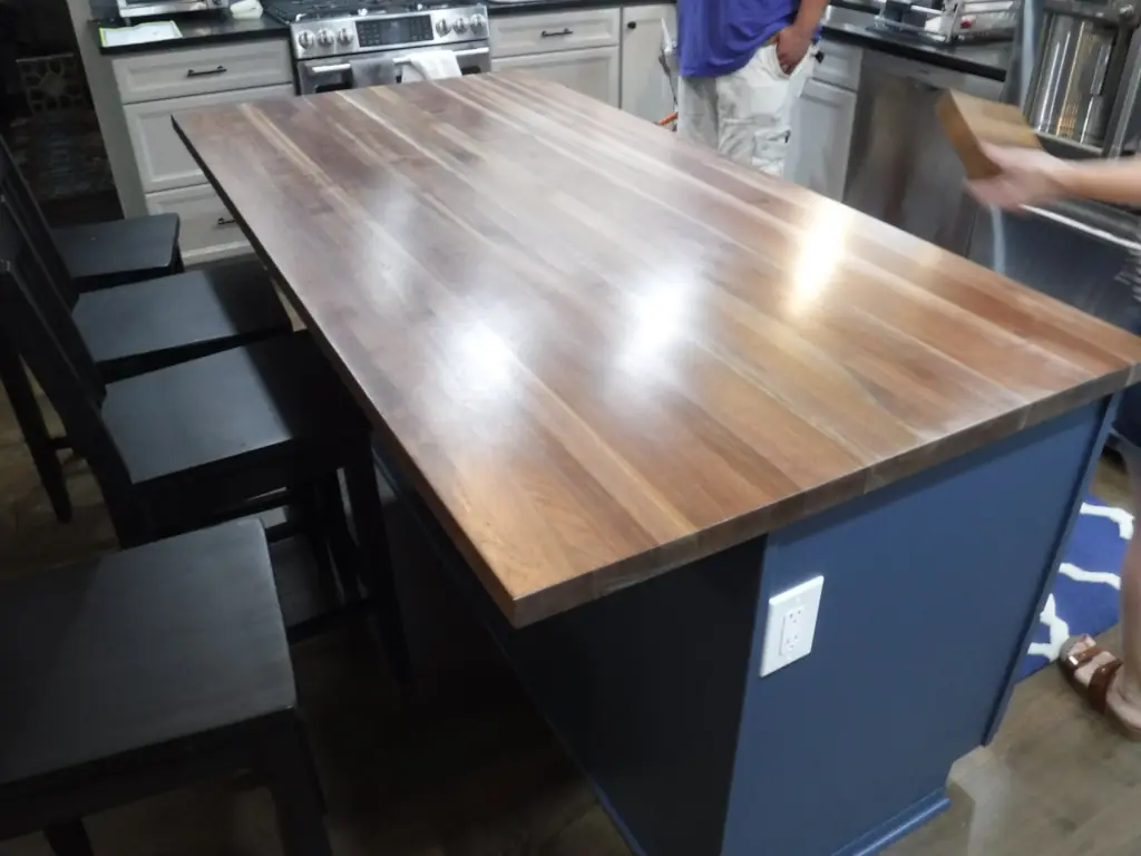 Black walnut wood countertop with an eased edge on a kitchen island with bar seating.