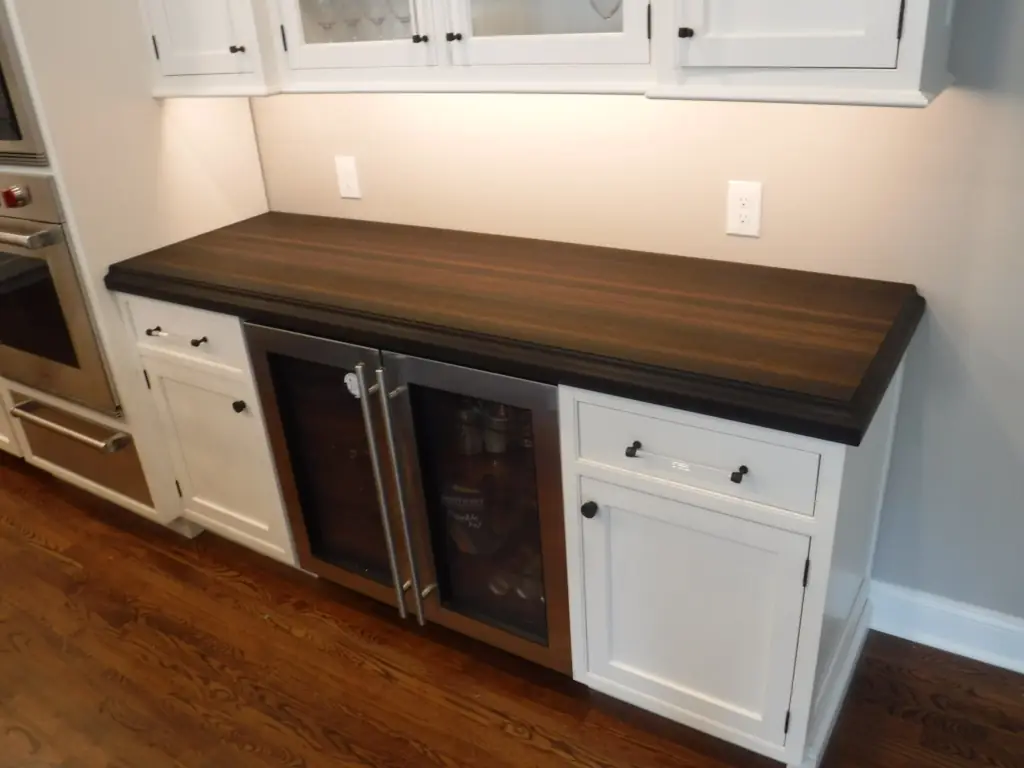 Peruvian walnut wood countertop with a thick kolossal edge above a beverage refrigerator.