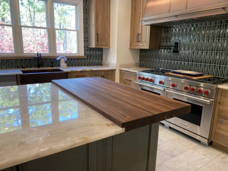Wood waterfall countertop extension off a stone kitchen island near a stainless steel range.