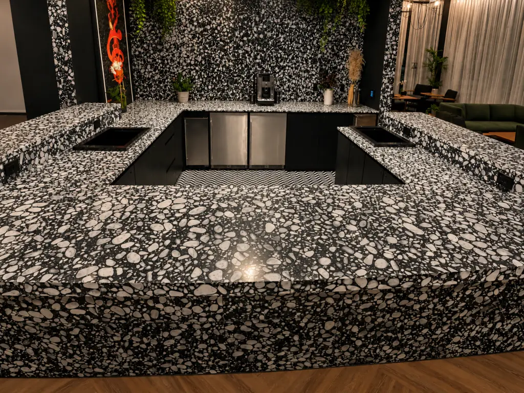 Bold black and white terrazzo bar top with matching wall panels in a modern lounge setting.